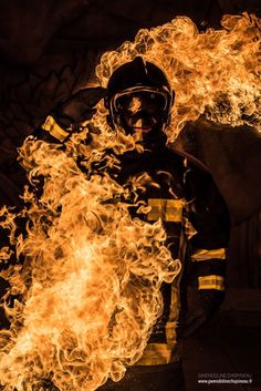 a firefighter in full uniform with flames coming out of his chest and hands behind him