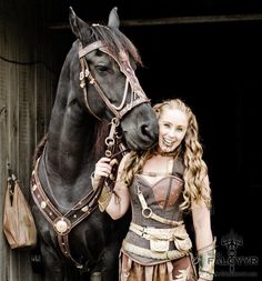 a woman standing next to a brown horse