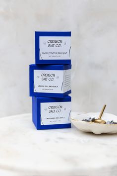 three blue boxes sitting on top of a white table next to a bowl and spoon