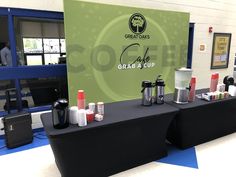 there is a table with cups on it in front of a sign that says grab and cup