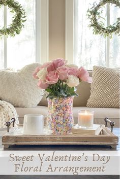 a coffee table with flowers and candles on it in front of a window that says sweet valentine's day floral arrangement