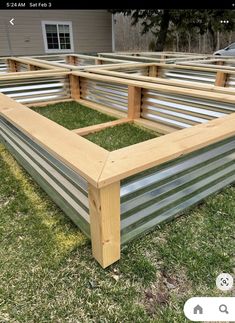 a wooden bed frame sitting on top of grass in front of a building with metal slats