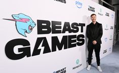 a man standing in front of a white wall with the words beast games on it