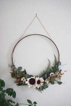 a circular wreath with flowers and greenery hangs on the wall