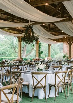 the tables are set up with white linens and greenery for an outdoor wedding reception