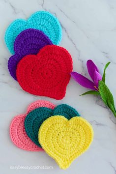 crocheted heart coasters on a marble surface with purple flowers in the background