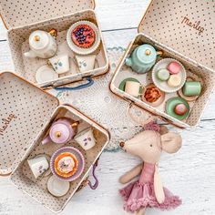 three tins filled with miniature items sitting on top of a white table next to each other