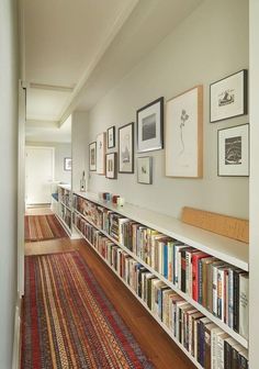 a long bookshelf filled with lots of books on top of a wooden floor