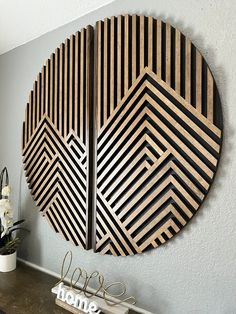 two wooden wall art pieces on the wall above a table with flowers in vases