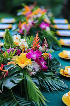 the table is set with yellow plates and colorful flower arrangements on green tablescloths