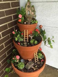 three tiered planters filled with plants and miniature garden accessories on the side of a house