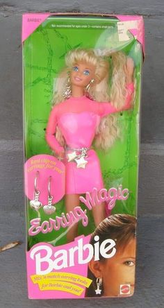 the barbie doll is wearing a pink dress and silver jewelry, but she's still in her original box