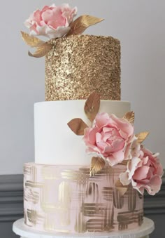 an image of a wedding cake with pink flowers on the top and gold leaves on the bottom