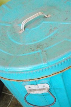 an old blue metal box sitting on the ground next to a tile floor and wall