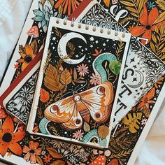 two notebooks with colorful designs on them sitting next to each other, one has a butterfly and the other is a letter c