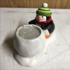 a snowman and penguin figurine sitting next to each other on a counter