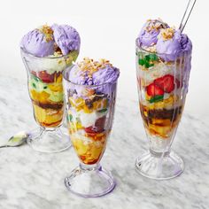 three glasses filled with dessert sitting on top of a marble counter next to each other