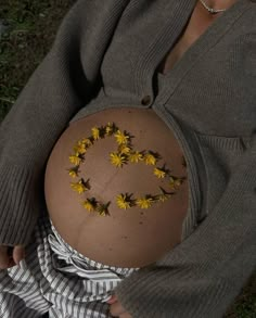 a pregnant belly with yellow flowers on it's side and the word love spelled in the middle