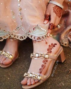 a woman with henna on her feet wearing high heeled sandals and gold jewelry