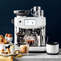 an espresso machine sitting on top of a counter next to plates and cups