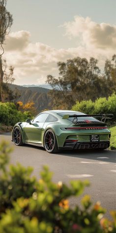 the green sports car is parked on the side of the road in front of some bushes