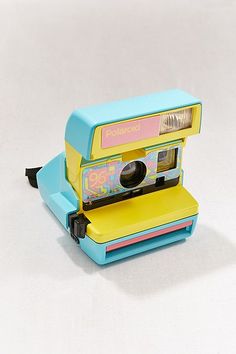 an old fashioned polaroid camera sitting on top of a white surface with the lens up