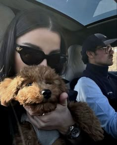 a woman holding a dog in her lap while sitting in the back seat of a car