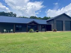 a large gray house sitting on top of a lush green field