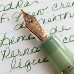 a fountain pen sitting on top of a piece of paper with writing in green ink