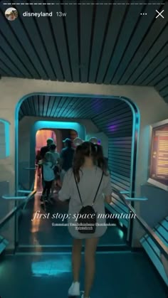 a woman walking down a hallway in a white shirt and black skirt with the words first stop space mountain on it