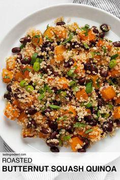 a white plate topped with black beans and quinoa next to a glass of orange juice