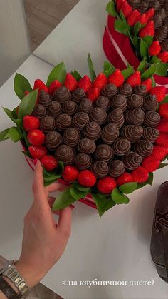 a heart shaped chocolate cake with strawberries on top and green leaves in the shape of a heart