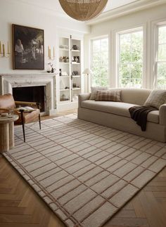 a living room filled with furniture and a large rug on the floor in front of a fire place