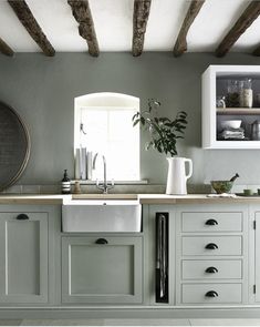 a kitchen with white cabinets and gray walls, an open window is above the sink