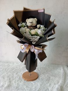 a bouquet of flowers with a teddy bear in the center and ribbon around the top