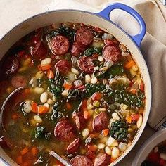 sausage, bean and spinach soup in a blue pot on a white tablecloth