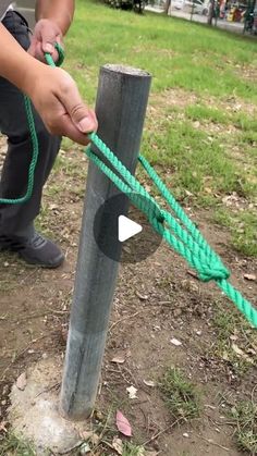 a person tying a rope around a pole