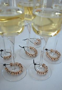 four wine glasses filled with white wine and wooden coasters that spell out the word booze