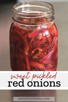 a jar filled with red onions sitting on top of a table