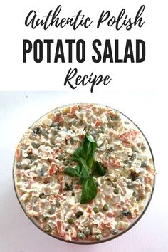 a bowl filled with potato salad on top of a white table next to a green leaf