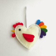 a white heart shaped ornament with a colorful rooster on it's side