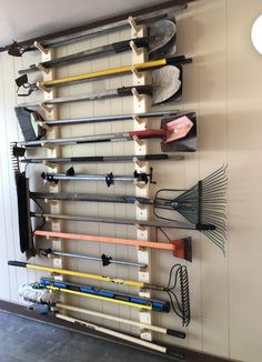 a wall mounted rack with many different types of garden tools hanging on it's sides