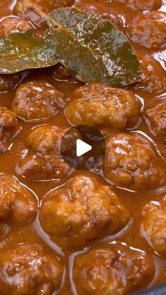 the meatballs are covered in sauce and garnished with green leafy leaves