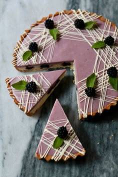 a piece of cake with white icing and blackberries on top is cut into pieces