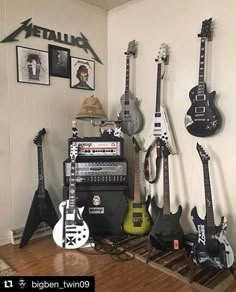 guitars and amps are lined up against the wall in a room with white walls