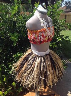 a mannequin wearing a dress made out of grass and beads with flowers on it