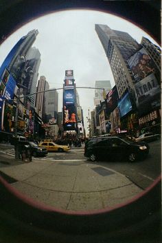 a city street filled with lots of tall buildings and cars driving down it's sides