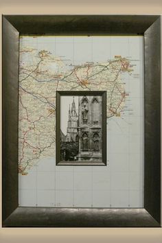 a framed map with a black frame and a brown border around it, in front of a white wall