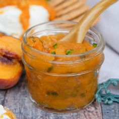 a spoon in a jar filled with peaches and green onions on a table next to sliced peaches