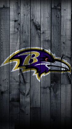 the baltimore ravens logo on a wooden fence with dark wood planks in the background